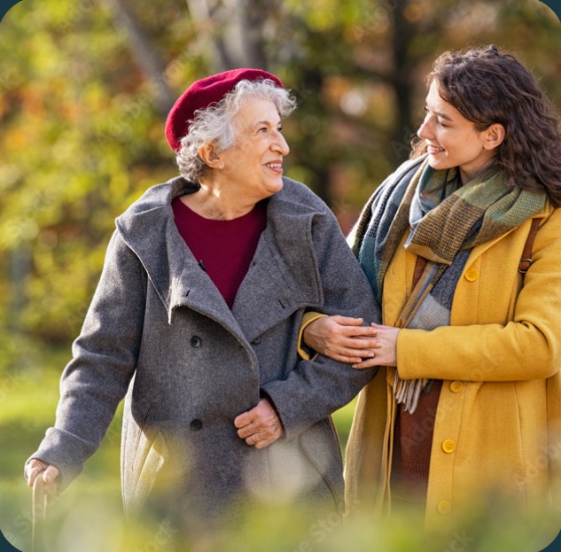 A younger woman walking arm in arm with an older woman in an autumn park